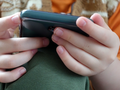 dziecko trzyma w ręce telefon komórkowy