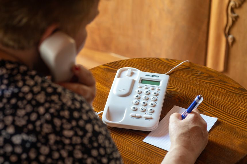Seniorka rozmawia przez telefon stacjonarny
