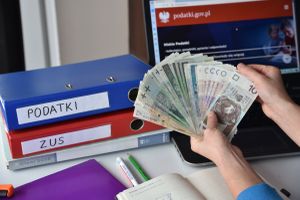 pieniądze i skoroszyty z napisami podatki i ZUS