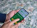strona logowania do PUE ZUS na smartfonie trzymanym nad pieniędzmi
