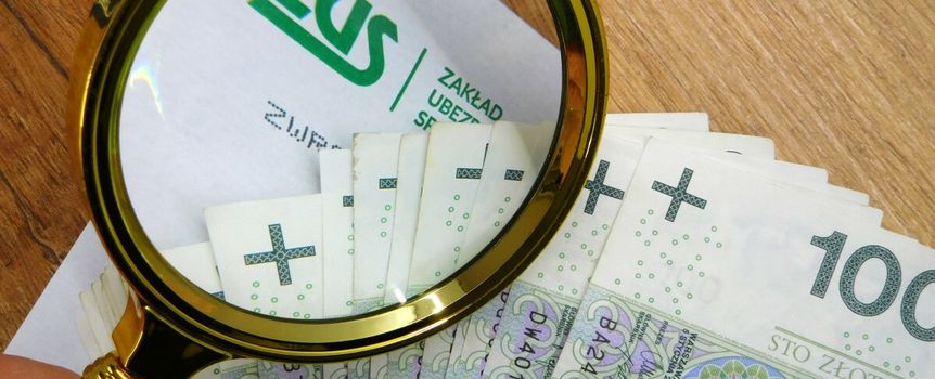 pieniądze i koperta z logo ZUS pod lupą