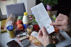 paragon po zakupach w ręku na tle produktów spożywczych