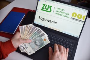 komputer ze stroną ZUS i pieniądze w ręku