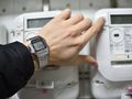 ręką z zegarkiem na tle liczników prądu elektrycznego