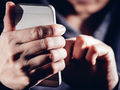 haker trzyma w dłoniach telefon komórkowy