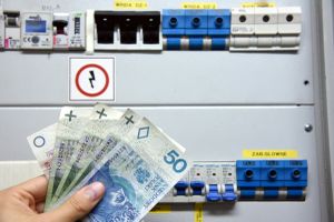 pieniądze trzymane przed tablicą bezpieczników