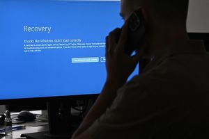 mężczyzna z telefonem przed ekranem z BSOD
