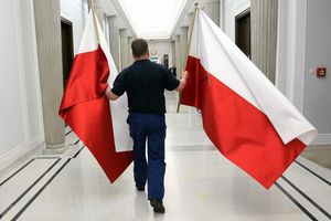 mężczyzna niosący dwie polskie flagi w korytarzu sejmowym