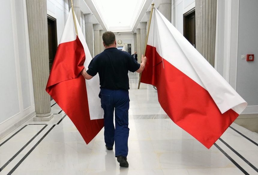mężczyzna niosący dwie polskie flagi w korytarzu sejmowym