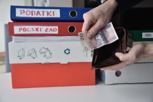 pieniądze, portfel i segregatory z napisami podatki i Polski Ład
