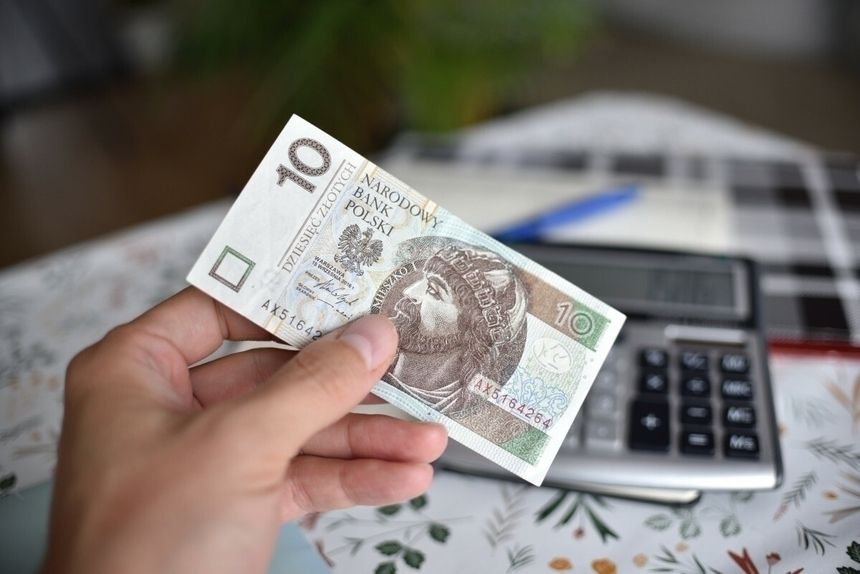 10 zł trzymane w ręku przed kalkulatorem