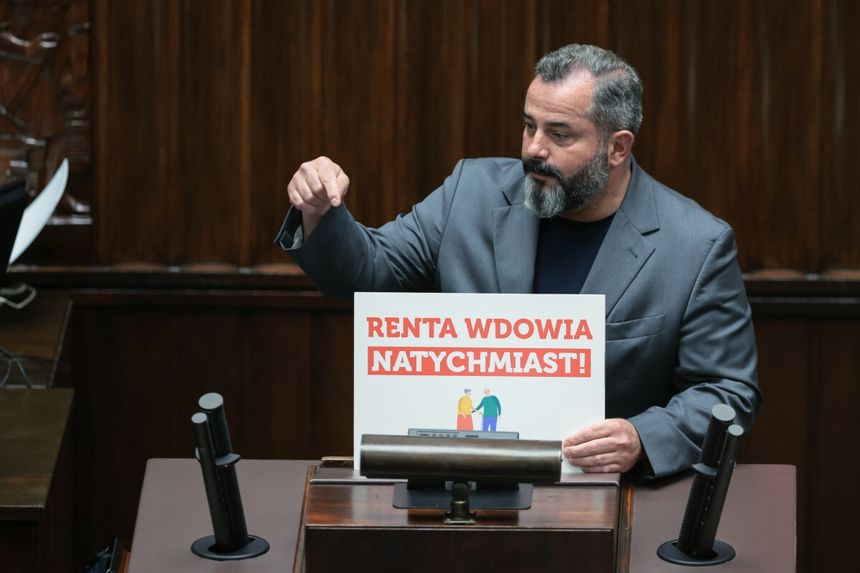 Arkadiusz Iwaniak z tabliczną "renta wdowia natychmiast" na mównicy sejmowej