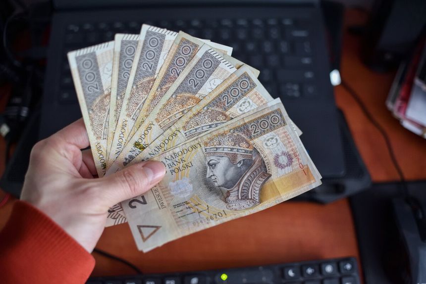 Pieniądze trzymane w ręku przed komputerem