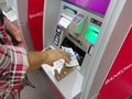mężczyzna wypłacający pieniądze z bankomatu