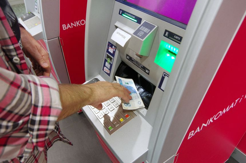 mężczyzna wypłacający pieniądze z bankomatu