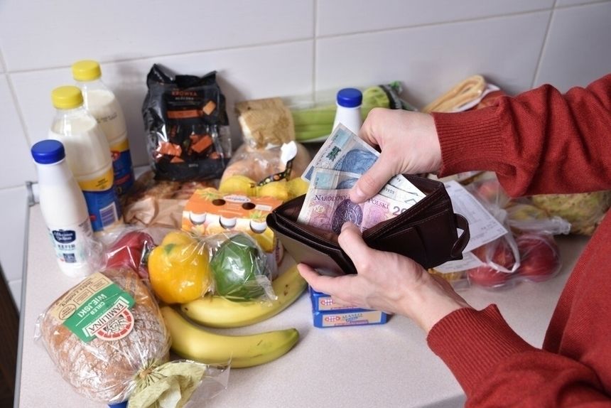 pieniądze wyciągane z portfela na tle produktów spożywczych