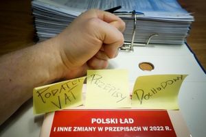 zaciśnięta pięść i karteczki z napisami podatek VAT, dochodowy, polski ład