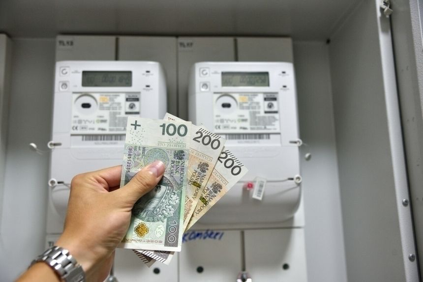 pieniądze trzymane przed licznikiem prądu