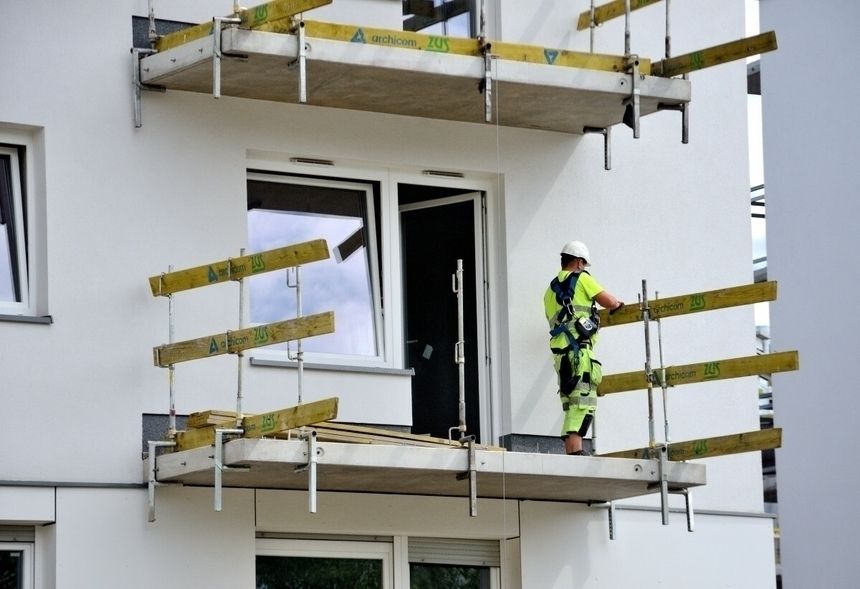 budowlaniec na balkonie budowanego bloku mieszkalnego