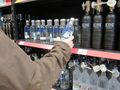 mężczyzna sięgający po butelkę wódki w sklepie
