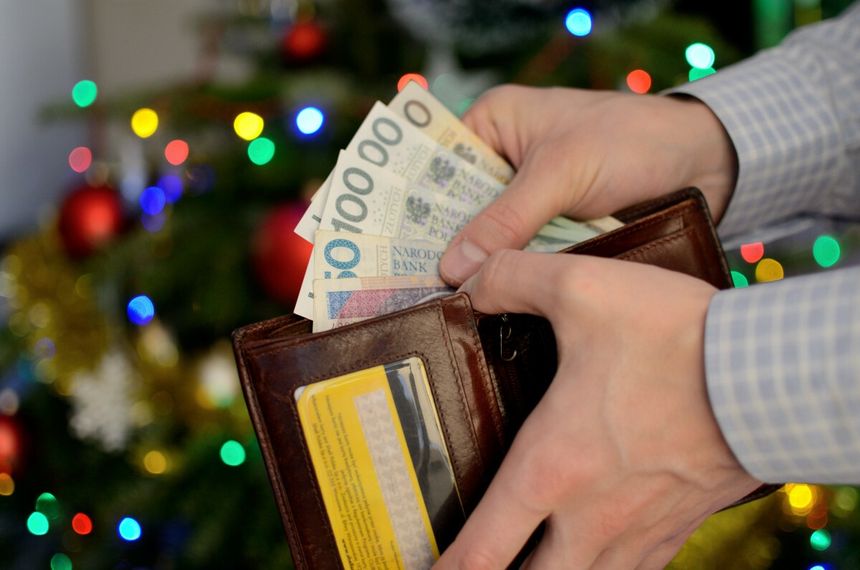 pieniądze wyciągane z portfela przed choinką