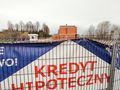 baner o kredytach hipotecznych rozwieszony na ogrodzeniu budowy