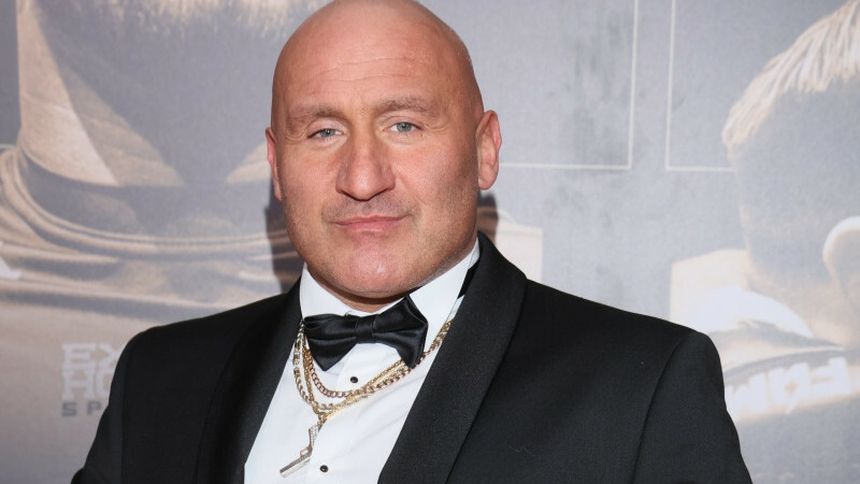 Marcin Najman w garniturze z muszką, z krótkimi włosami, z wyrazem pewności siebie.