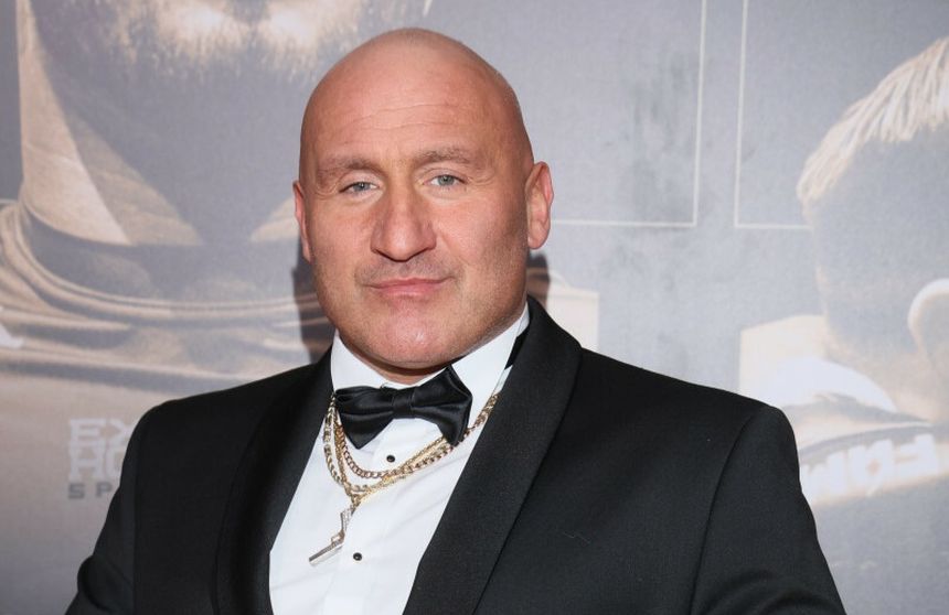 Marcin Najman w garniturze z muszką, z krótkimi włosami, z wyrazem pewności siebie.