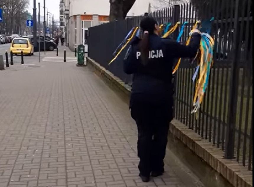 policjantka usuwająca ukraińskie barwy z ogrodzenia przez rosyjską ambasadą