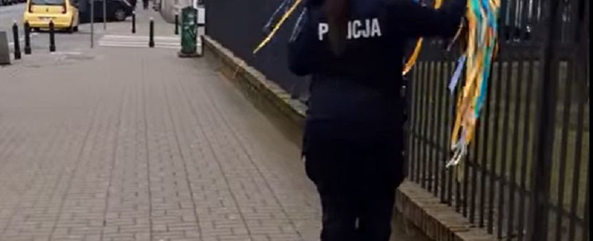 policjantka usuwająca ukraińskie barwy z ogrodzenia przez rosyjską ambasadą
