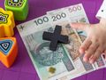 pieniądze, klocek plus i ręka dziecka