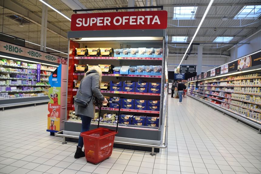 kobieta przed regałem z promocjami w sklepie