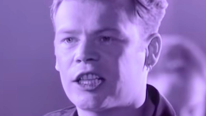 Mężczyzna z krótkimi, jasnymi włosami, mówi z pasją na fioletowym tle.