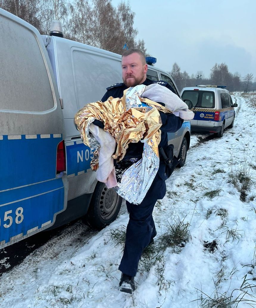 Policjant niesie zmarznięte dziecko