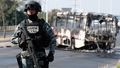 Członek meksykańskiej Gwardii Narodowej pełni wartę przy autobusie spalonym przez członków kartelu CJNG