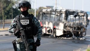 Członek meksykańskiej Gwardii Narodowej pełni wartę przy autobusie spalonym przez członków kartelu CJNG