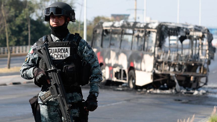 Członek meksykańskiej Gwardii Narodowej pełni wartę przy autobusie spalonym przez członków kartelu CJNG
