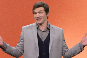 Connor Storrie w skeczu SNL na pomarańczowym tle