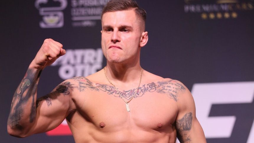 Alan Kwieciński, ubrany w spodenki, przyjmuje zdecydowaną postawę na wadze.