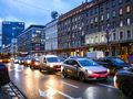 Zatłoczona ulica w mieście, oświetlone budynki i zaparkowane samochody w zmierzchu
