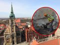 Zdjęcie przedstawia widok na miasto z wieżą kościoła i prace archeologiczne w tle