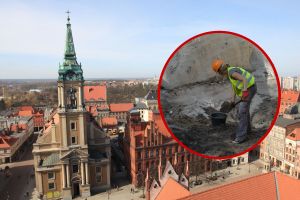 Zdjęcie przedstawia widok na miasto z wieżą kościoła i prace archeologiczne w tle