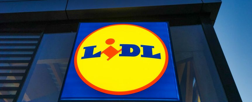 Logo sklepu Lidl na jasnym tle, umieszczone na ścianie budynku.