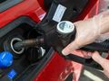 Osoba w rękawiczkach tankuje samochód na stacji paliw, widoczne paliwo typu diesel.