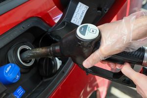 Osoba w rękawiczkach tankuje samochód na stacji paliw, widoczne paliwo typu diesel.