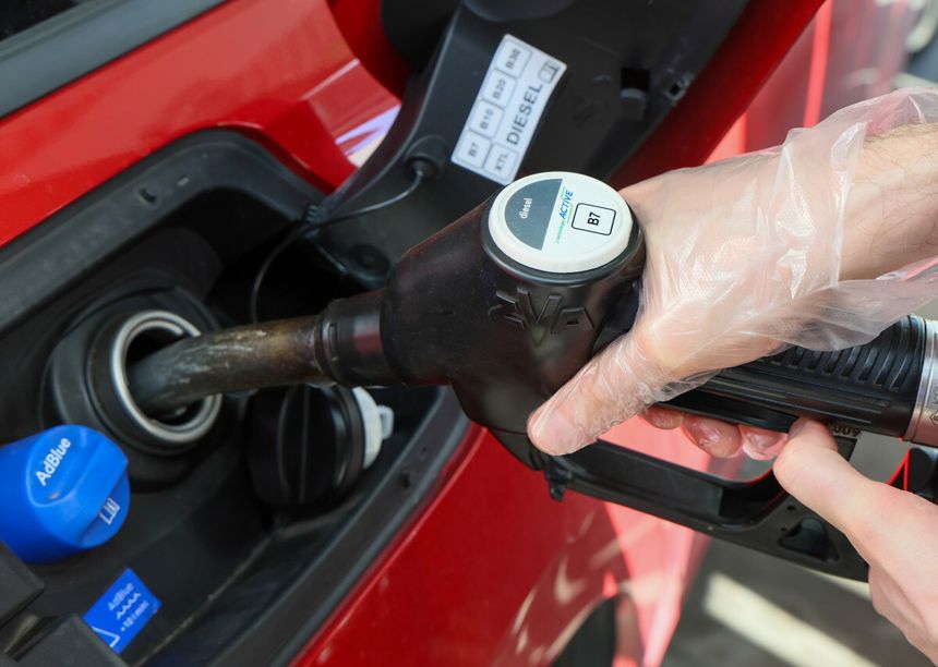 Osoba w rękawiczkach tankuje samochód na stacji paliw, widoczne paliwo typu diesel.