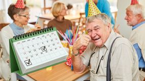 Grupa starszych osób na przyjęciu, mężczyzna w okularach uśmiecha się do kamery