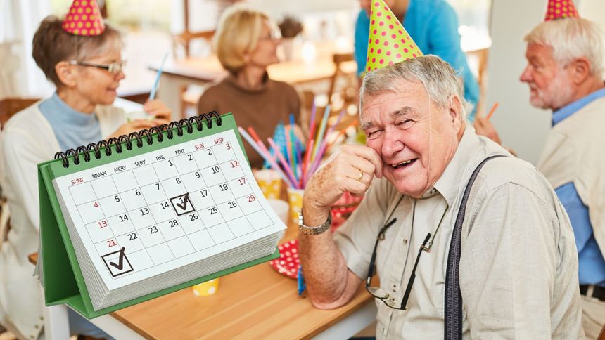 Grupa starszych osób na przyjęciu, mężczyzna w okularach uśmiecha się do kamery