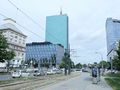 Nowoczesne budynki w mieście, w tle chmurne niebo, ruch uliczny na pierwszym planie.