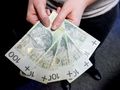 Ręce trzymające pięć banknotów o nominale 100 złotych, widoczny portret króla Stanisława Augusta.